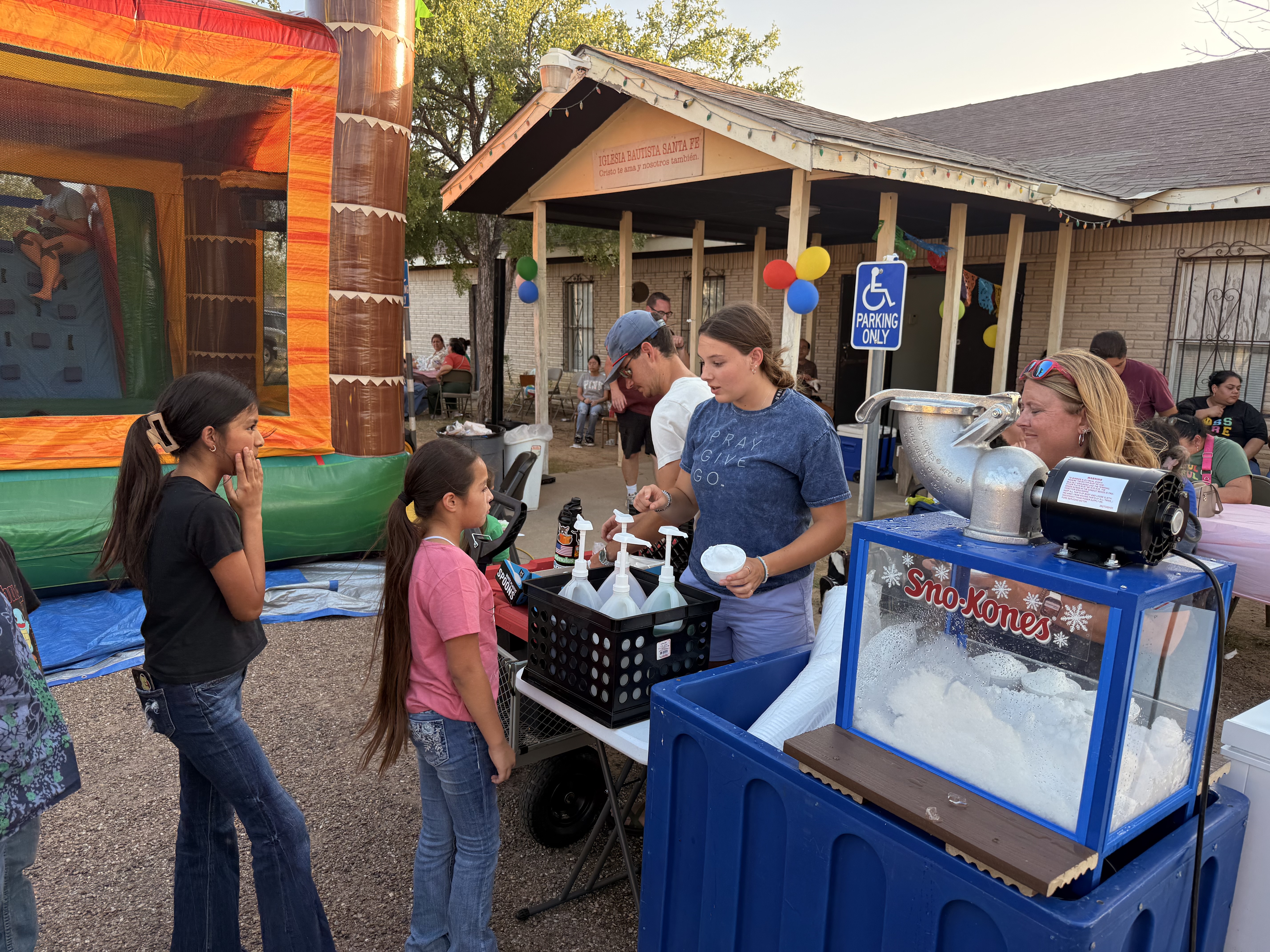 CVBC volunteers serving sno cones beside an inflatable